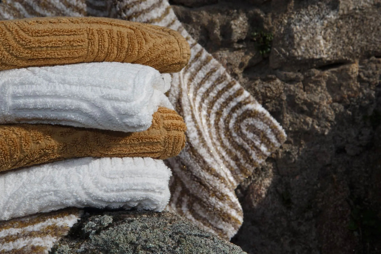 A&H Olly Towels in 103 Ivory & 840 Gold. A&H Petal Bath Rug in 770 Linen