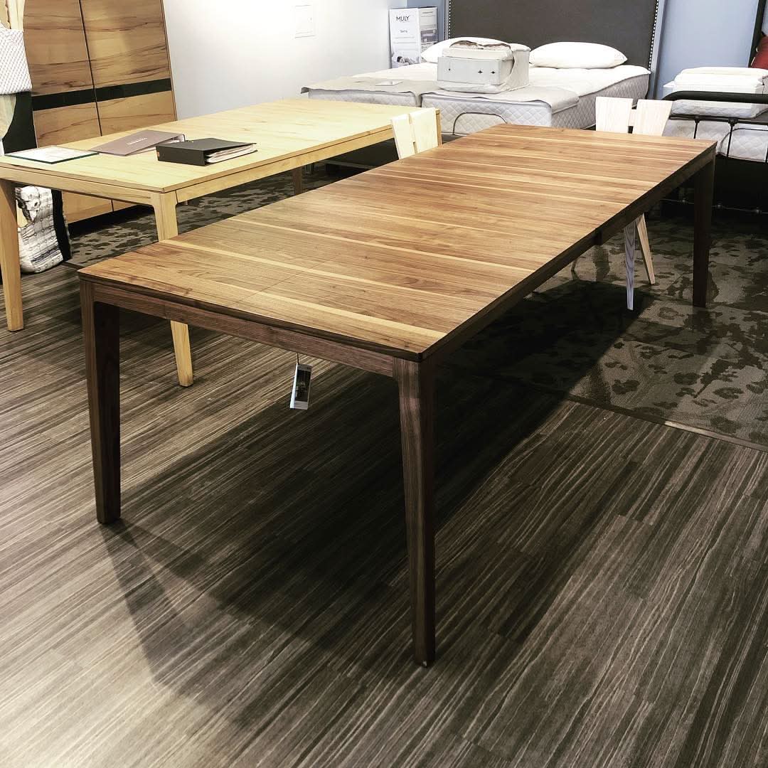 Foreground: TEAM 7 mylon table in walnut. Background: mylon table in beech heartwood - photo in our Calgary showroom