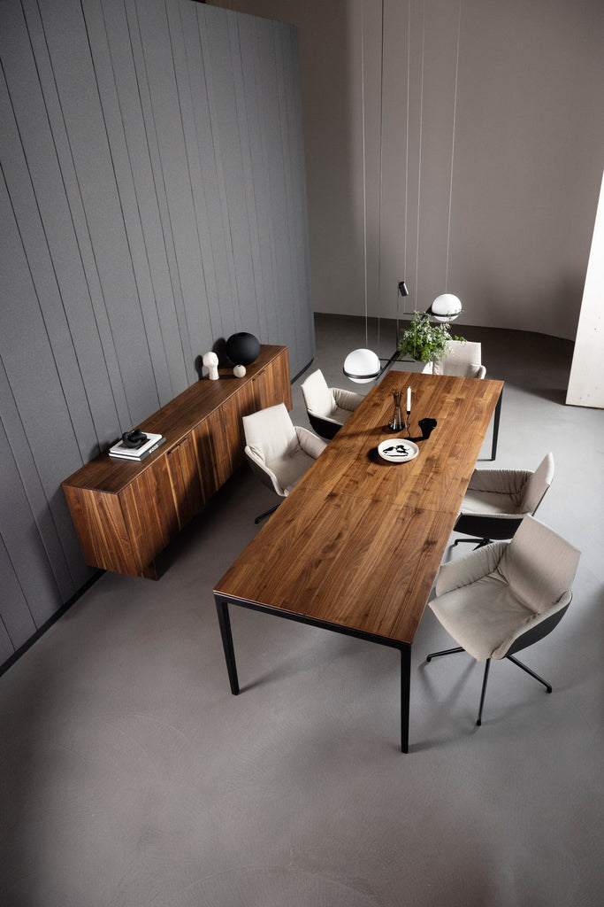 The tak table now features a continuous wood grain from tabletop to cushioned extension. Shown here in walnut w/ matte black frame, lui léger chairs and filigno sideboard. photo: TEAM 7