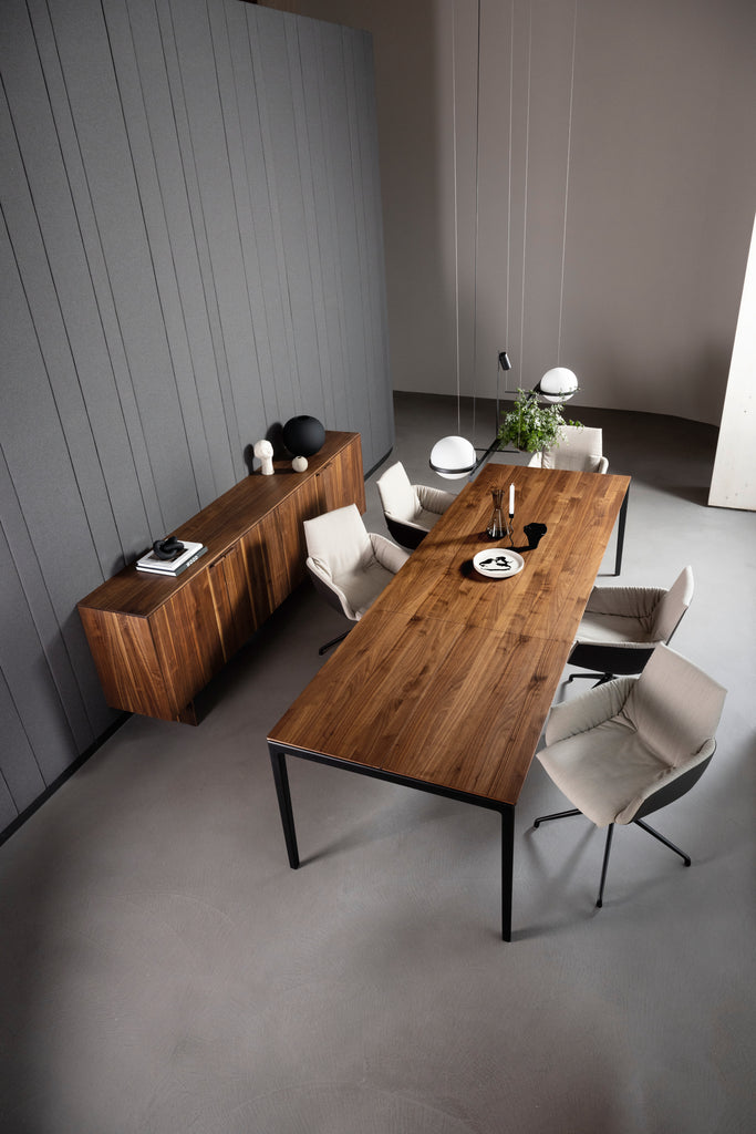 The tak table now features a continuous wood grain from tabletop to cushioned extension. Shown here in walnut w/ matte black frame, lui léger chairs and filigno sideboard. photo: TEAM 7