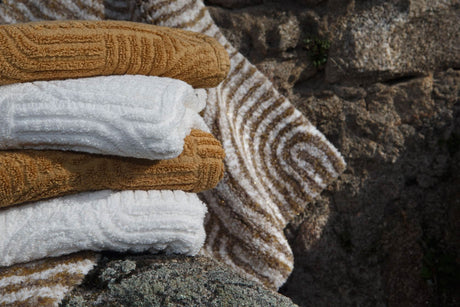 A&H Olly Towels in 103 Ivory & 840 Gold. A&H Petal Bath Rug in 770 Linen