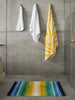 The A&H Santa Cruz Bath Rug in 302 Lagoon. Towels left: Surf Hair Towel in 165 Apple Green, Surf Bath Towel in 302 Lagoon and Zebra Beach Towel in 830 Banane